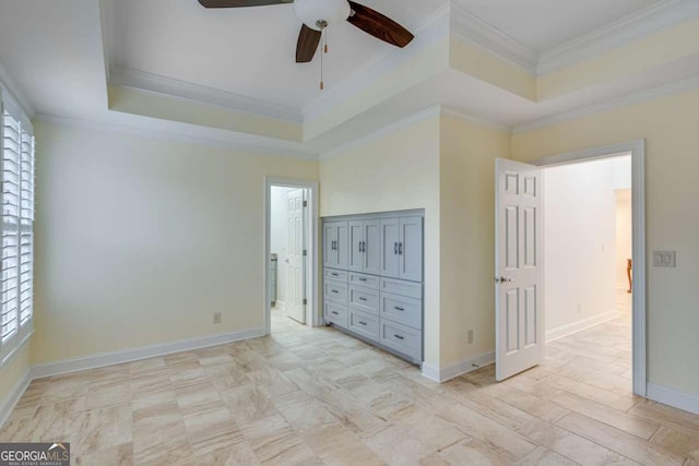 unfurnished bedroom featuring a ceiling fan, a raised ceiling, baseboards, and ornamental molding