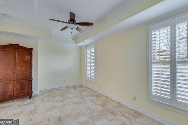 unfurnished bedroom featuring crown molding, a ceiling fan, baseboards, and a tray ceiling