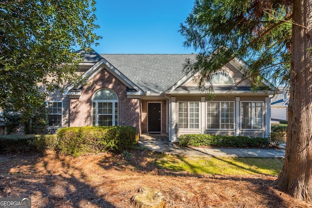 ranch-style house featuring brick siding and roof with shingles