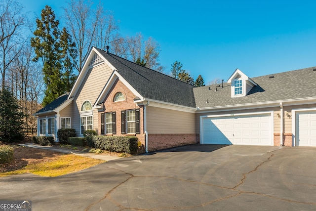 view of front of property featuring a garage, brick siding, driveway, and a shingled roof