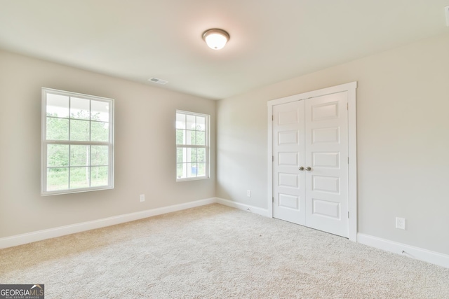 unfurnished bedroom featuring a closet, visible vents, baseboards, and carpet