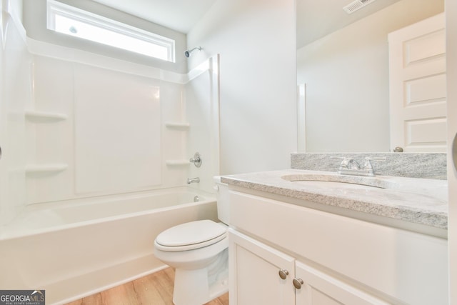 bathroom featuring wood finished floors, toilet, bathtub / shower combination, and vanity