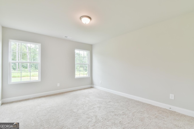 unfurnished room with carpet flooring, visible vents, and baseboards