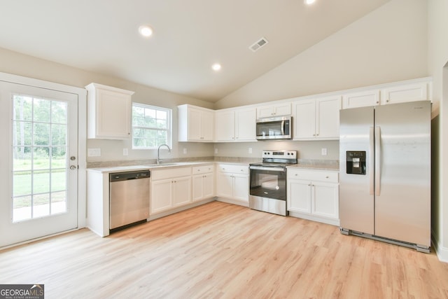 155 Berryman Rd, Hartwell, GA 30643 - kitchen featuring appliances with stainless steel finishes, light wood-style flooring, light countertops, white cabinetry, and vaulted ceiling
