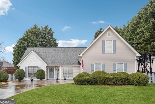 traditional home with a front yard, fence, and a shingled roof