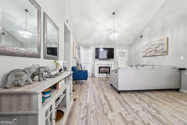 living area featuring wood finished floors, visible vents, high vaulted ceiling, a fireplace, and a notable chandelier