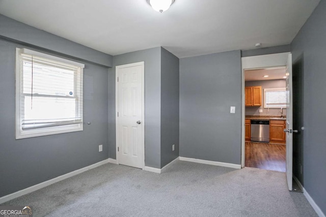 unfurnished bedroom with carpet flooring, baseboards, and a sink