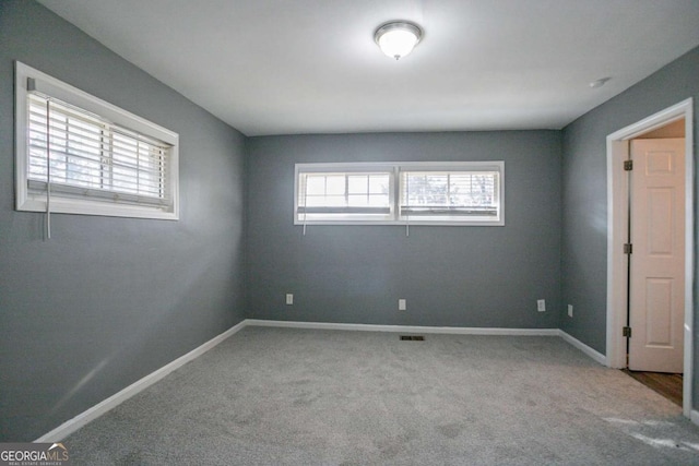 unfurnished room with carpet flooring, baseboards, and visible vents