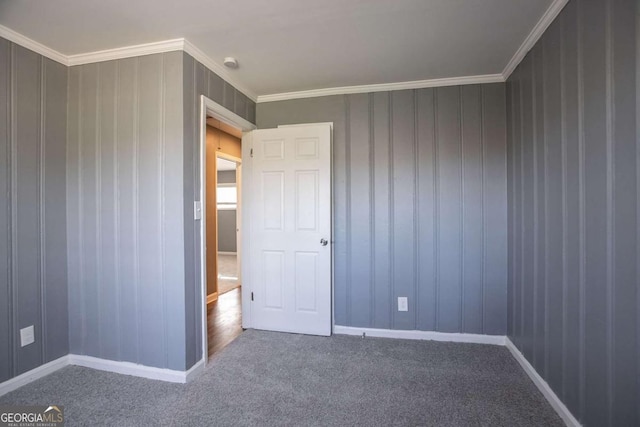 unfurnished bedroom with baseboards, crown molding, and carpet