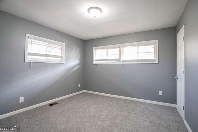 carpeted spare room featuring baseboards and visible vents