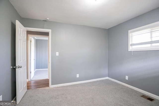 carpeted spare room with visible vents and baseboards