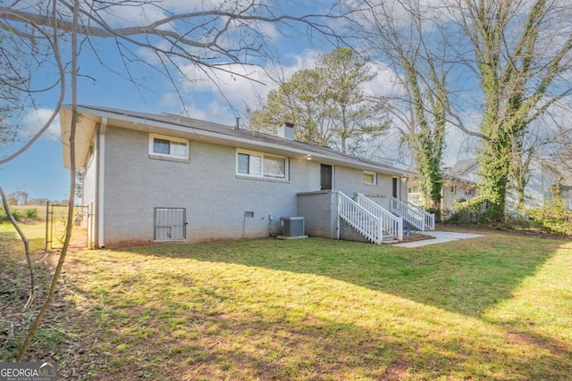 rear view of property featuring cooling unit, a chimney, crawl space, a lawn, and brick siding