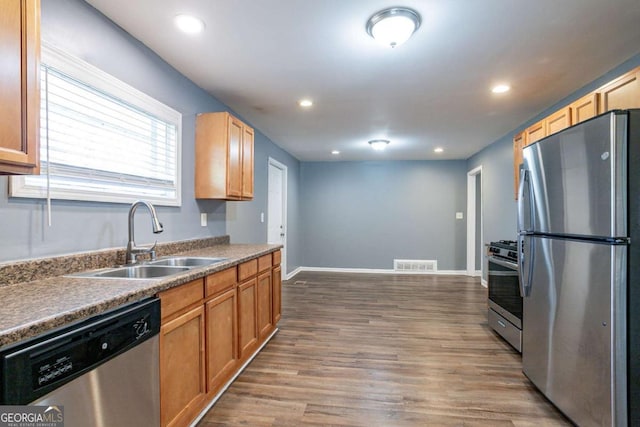 kitchen featuring wood finished floors, baseboards, visible vents, a sink, and appliances with stainless steel finishes