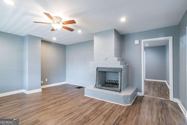 unfurnished living room with a brick fireplace, ceiling fan, baseboards, recessed lighting, and wood finished floors