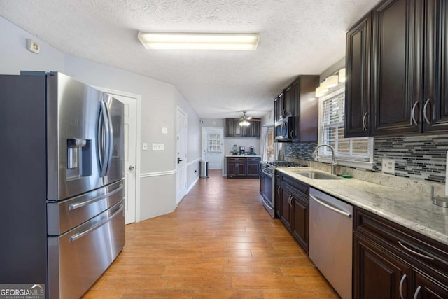 kitchen with light wood finished floors, stainless steel appliances, tasteful backsplash, and a sink