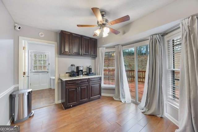 kitchen with light countertops, dark brown cabinets, light wood-type flooring, and ceiling fan