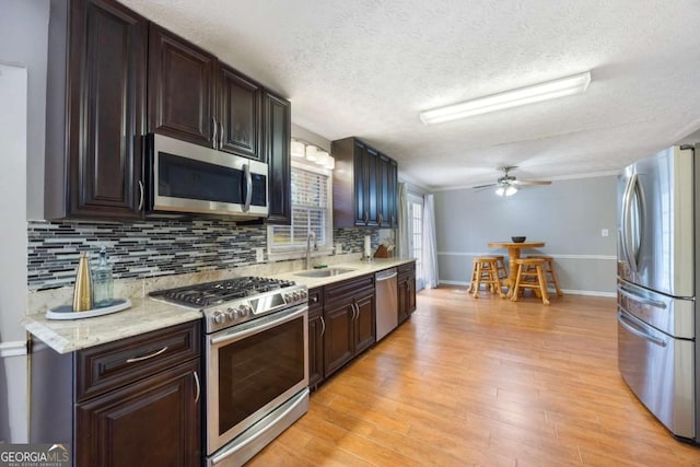 kitchen featuring light wood-type flooring, stainless steel appliances, light countertops, and a sink