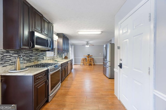 kitchen with light countertops, decorative backsplash, light wood-style flooring, stainless steel appliances, and a sink