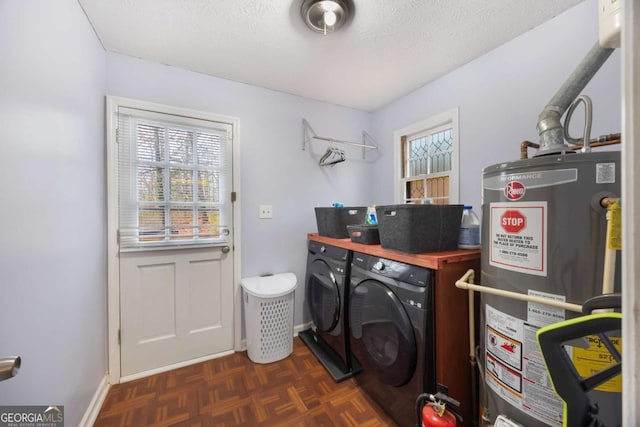 laundry area with a textured ceiling, washing machine and dryer, water heater, baseboards, and laundry area