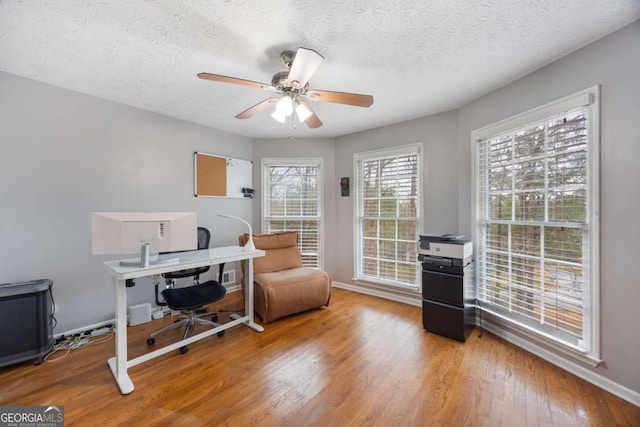 office area featuring a textured ceiling, baseboards, a ceiling fan, and wood finished floors