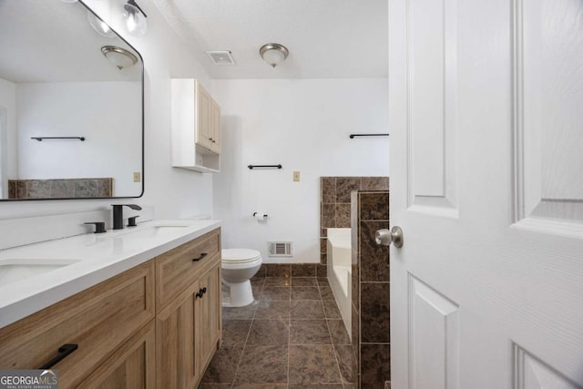 bathroom with a garden tub, toilet, visible vents, and a sink