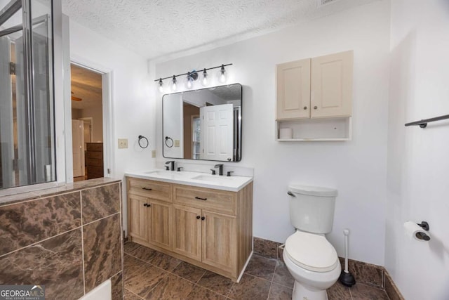 full bathroom featuring a sink, a textured ceiling, toilet, and double vanity