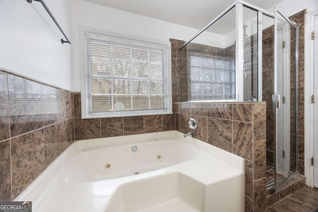 full bath featuring a textured ceiling, a stall shower, and a whirlpool tub