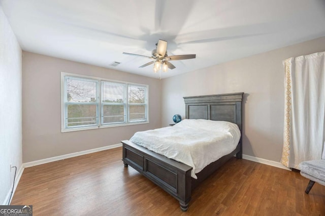 bedroom with ceiling fan, visible vents, baseboards, and wood finished floors