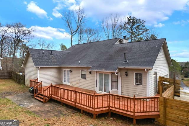 back of house featuring roof with shingles, a deck, a chimney, and fence