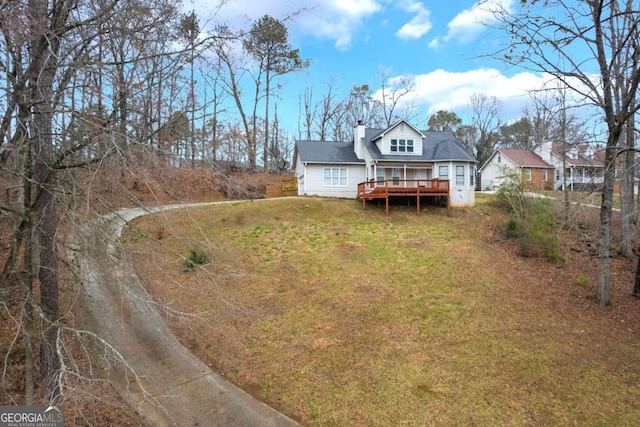 rear view of property with a yard, a chimney, and a deck