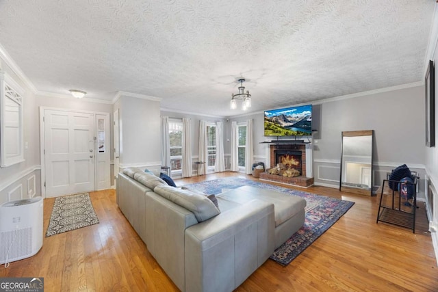 living area with a brick fireplace, wood finished floors, wainscoting, and ornamental molding