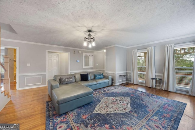 living area with a notable chandelier, stairway, a wainscoted wall, and wood finished floors