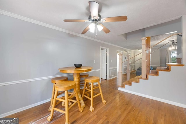 dining room with stairway, crown molding, baseboards, and wood finished floors