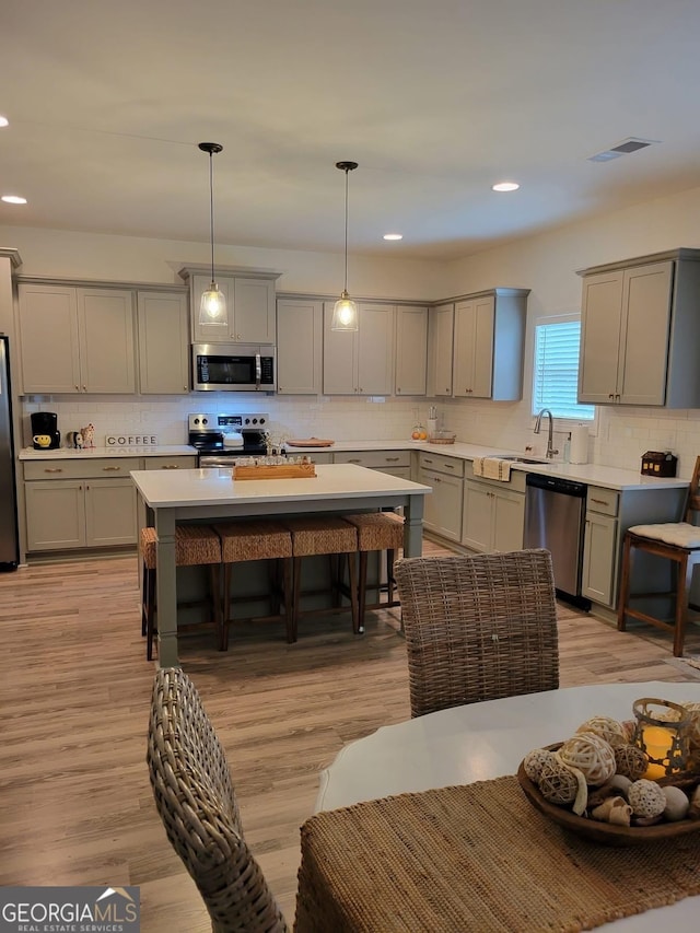 kitchen with stainless steel appliances, gray cabinetry, and light countertops