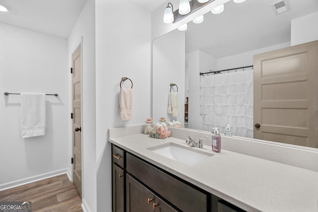 full bath with vanity, a shower with shower curtain, wood finished floors, visible vents, and baseboards