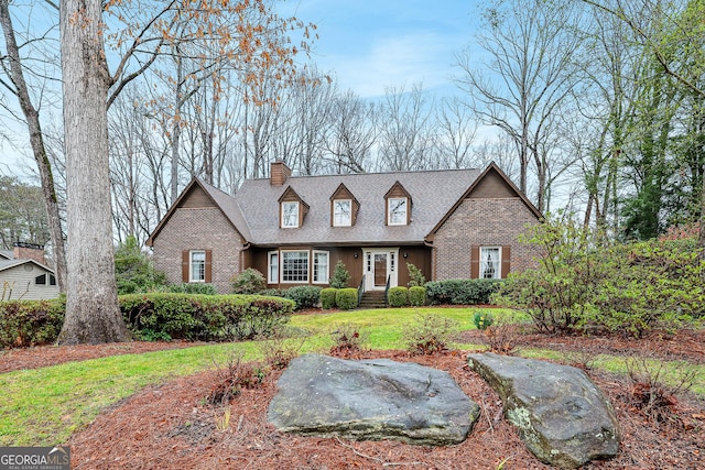 cape cod-style house with a chimney, brick siding, roof with shingles, and a front lawn