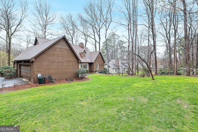 view of side of property featuring an attached garage, driveway, a chimney, and a yard