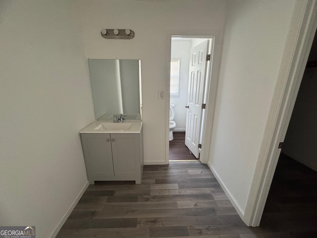 bathroom featuring toilet, vanity, baseboards, and wood finished floors