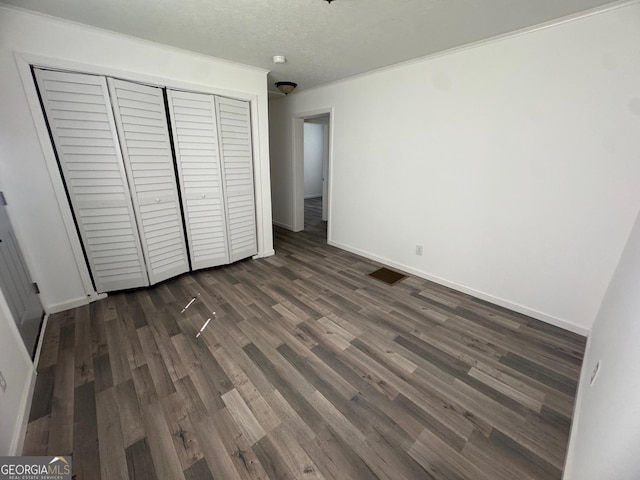 unfurnished bedroom featuring visible vents, baseboards, dark wood finished floors, a closet, and a textured ceiling