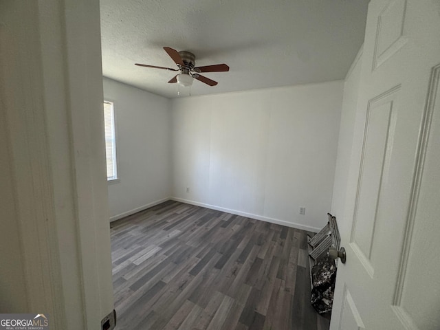 spare room featuring baseboards, a textured ceiling, dark wood finished floors, and a ceiling fan