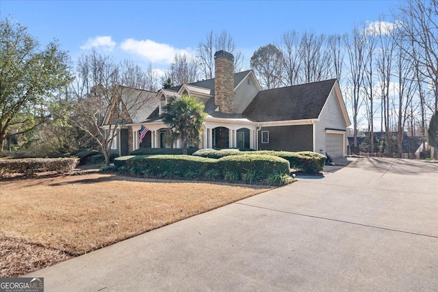 view of front of home with a front yard, an attached garage, driveway, and a chimney