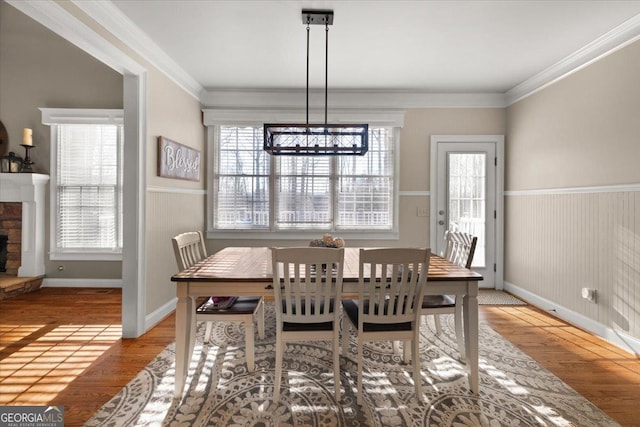 dining area featuring a fireplace, wood finished floors, and crown molding