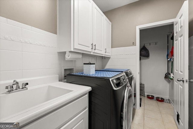 laundry area featuring washer and clothes dryer, light tile patterned floors, cabinet space, tile walls, and a sink