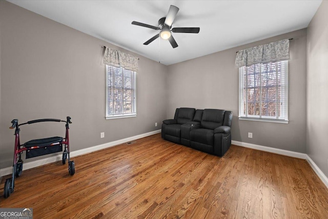 sitting room featuring a ceiling fan, plenty of natural light, wood finished floors, and baseboards