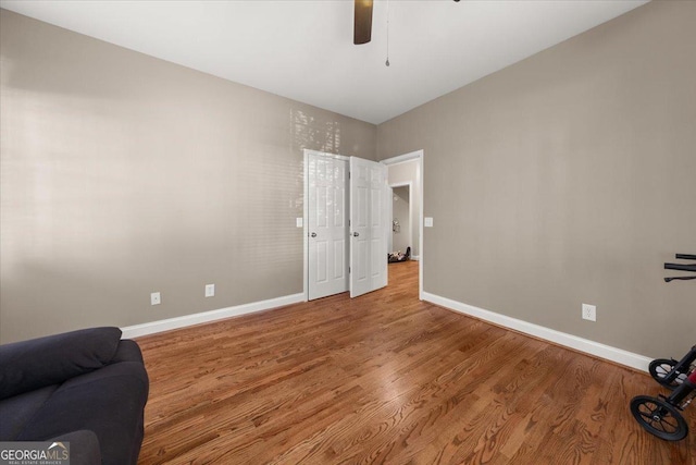 interior space featuring ceiling fan, baseboards, and wood finished floors