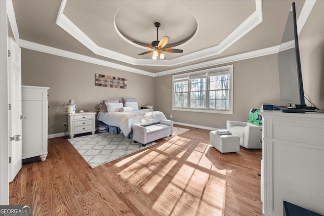 bedroom with crown molding, a tray ceiling, and wood finished floors