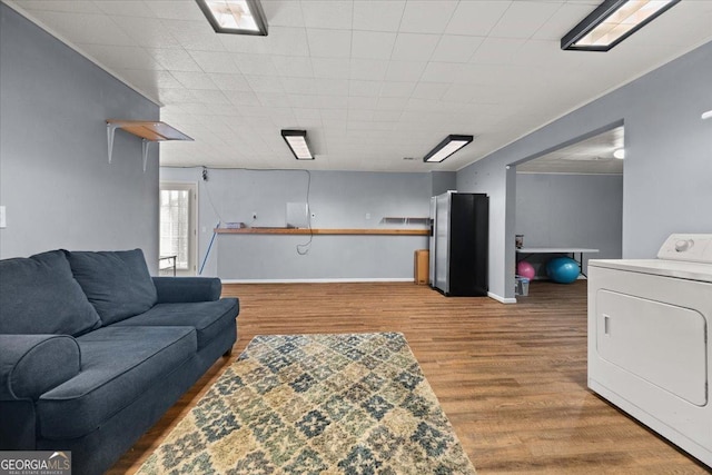 living area featuring washer / dryer, baseboards, and wood finished floors