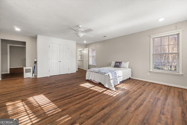 unfurnished bedroom with baseboards, multiple windows, a closet, and wood finished floors