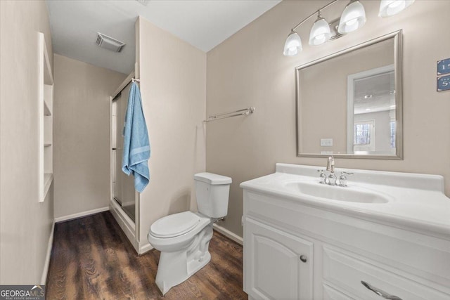 bathroom with visible vents, toilet, a stall shower, wood finished floors, and vanity