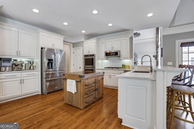 kitchen with a center island, a breakfast bar, white cabinets, stainless steel appliances, and a sink